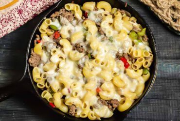 Skillet meal with pasta, thinly sliced steak, onions, peppers, and melted cheese.
