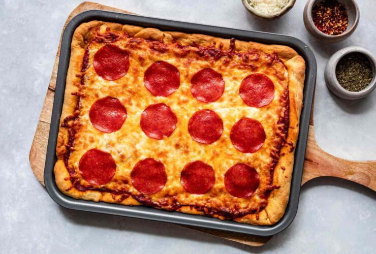 Homemade pizza baked on a sheet pan with assorted toppings.