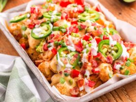 loaded tater tot nachos on large platter with melted cheese, ground beef, jalapeños, and fresh toppings