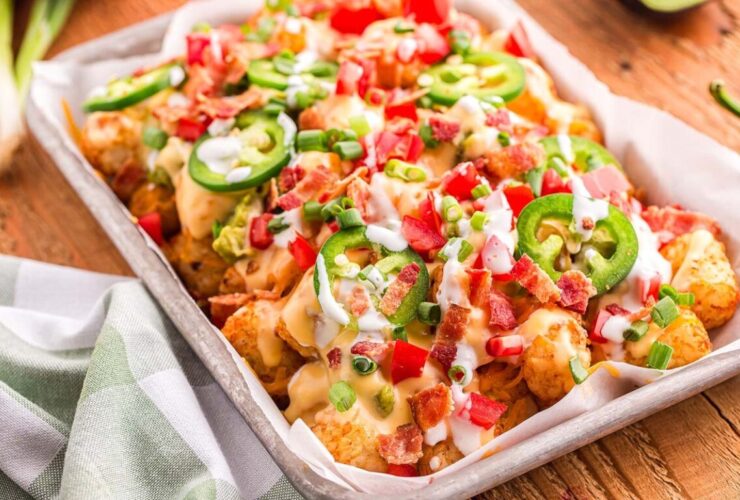 loaded tater tot nachos on large platter with melted cheese, ground beef, jalapeños, and fresh toppings