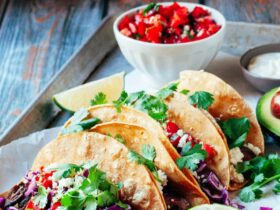 Perfectly grilled carne asada tacos on warm corn tortillas with fresh cilantro, diced onions, and lime wedges, beautifully plated on a rustic wooden board
