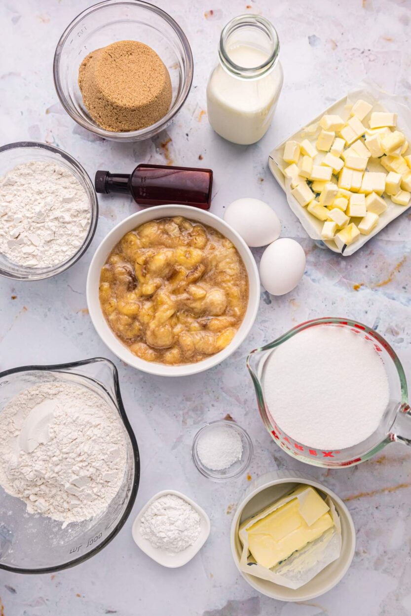 Ingredients laid out on marble counter including overripe bananas, chocolate chunks, flour, and measuring tools with mixing bowl
