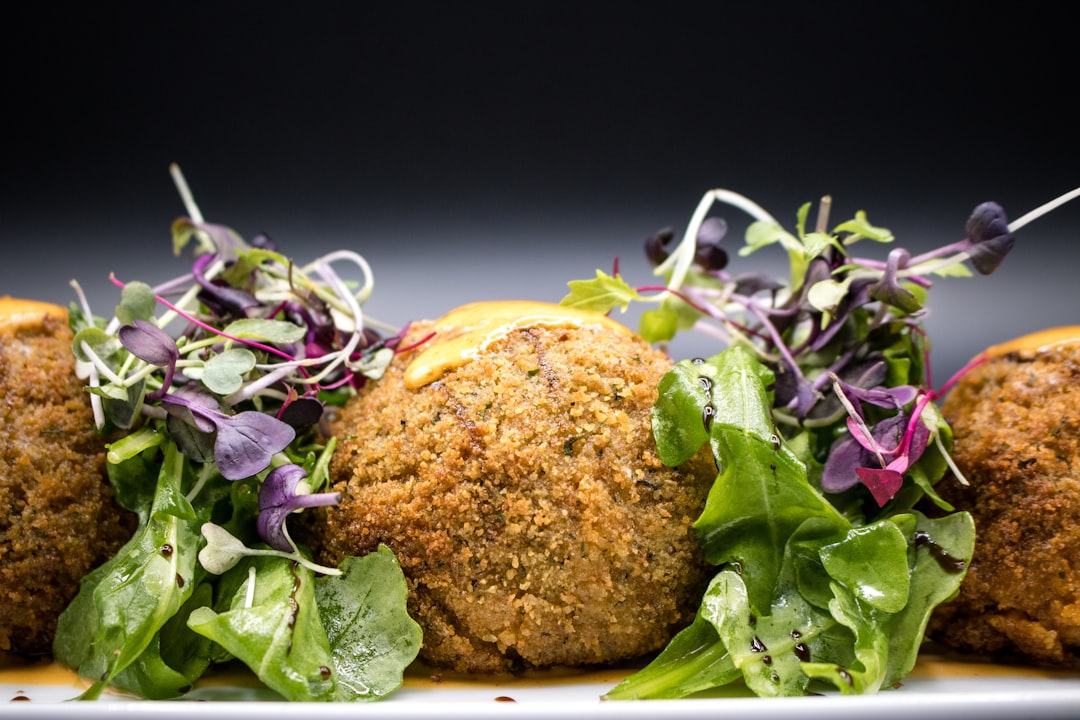 Golden crispy falafel balls arranged on a rustic wooden platter with fresh herbs, tahini drizzle, and colorful vegetables