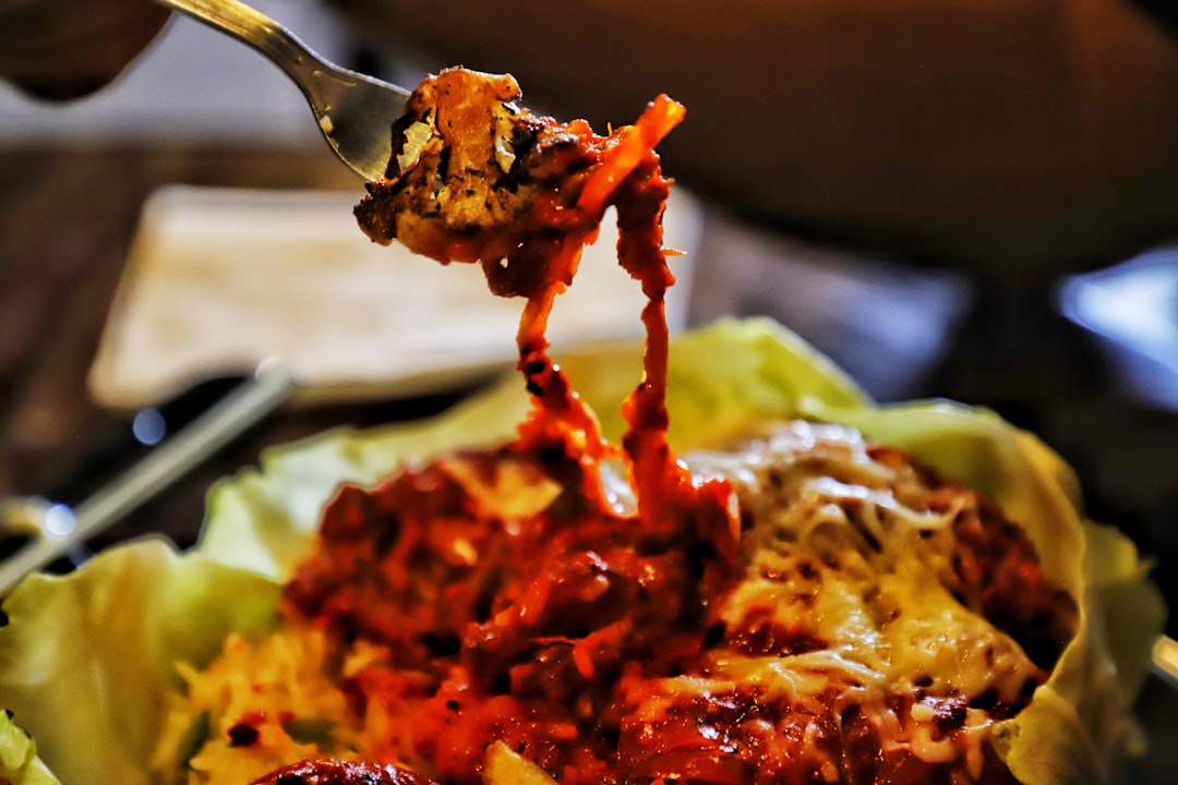 Close-up shot of perfectly shredded pulled pork being lifted with a fork, showing the tender, juicy strands with visible seasoning and glaze