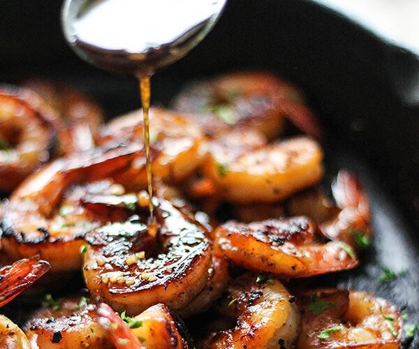 honey glazed shrimp in skillet with golden caramelized sauce and garnished with green onions and sesame seeds