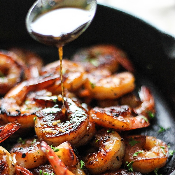honey glazed shrimp in skillet with golden caramelized sauce and garnished with green onions and sesame seeds