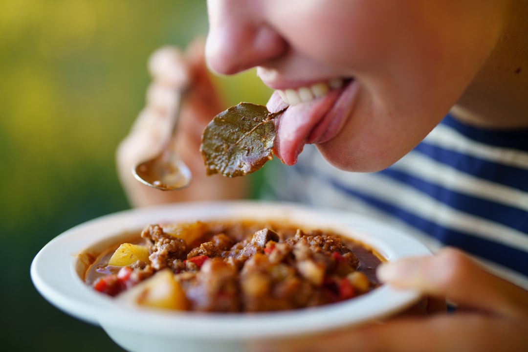 Close-up of fork lifting tender beef chunk from bowl of rich stew with steam rising