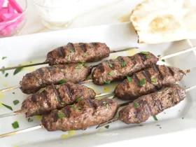Lebanese kafta kebabs on metal skewers with perfect char marks, garnished with fresh parsley and served on a rustic wooden platter with grilled vegetables