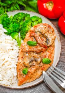 Marry Me Chicken served on elegant white plates with creamy sun-dried tomato sauce, fresh basil garnish, and golden seared chicken thighs