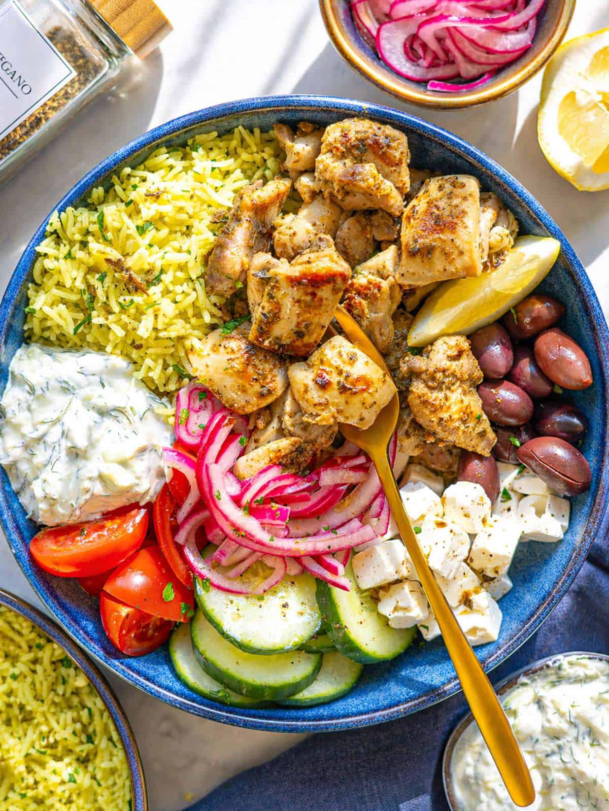 Mediterranean chicken bowl with golden herb-crusted chicken thighs, creamy tzatziki, colorful vegetables, and grains beautifully arranged in a rustic ceramic bowl