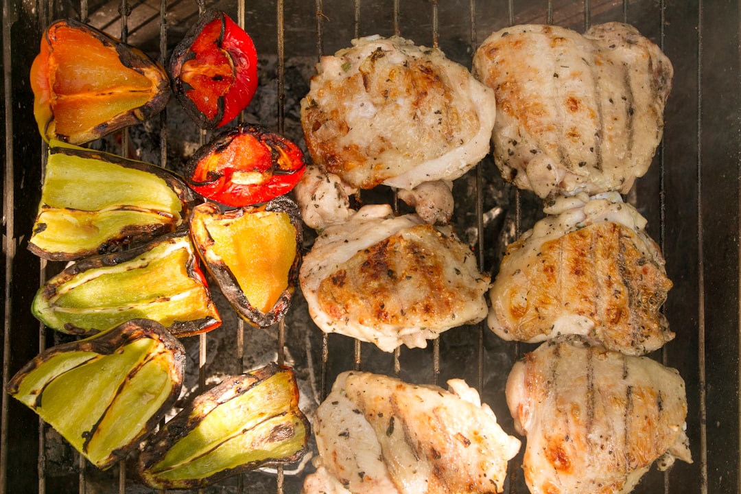 Raw marinated chicken thighs in a glass bowl showing the herb and oil coating, alongside fresh ingredients for tzatziki