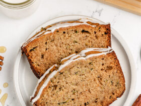 golden brown zucchini bread loaf sliced on wooden cutting board with butter and honey