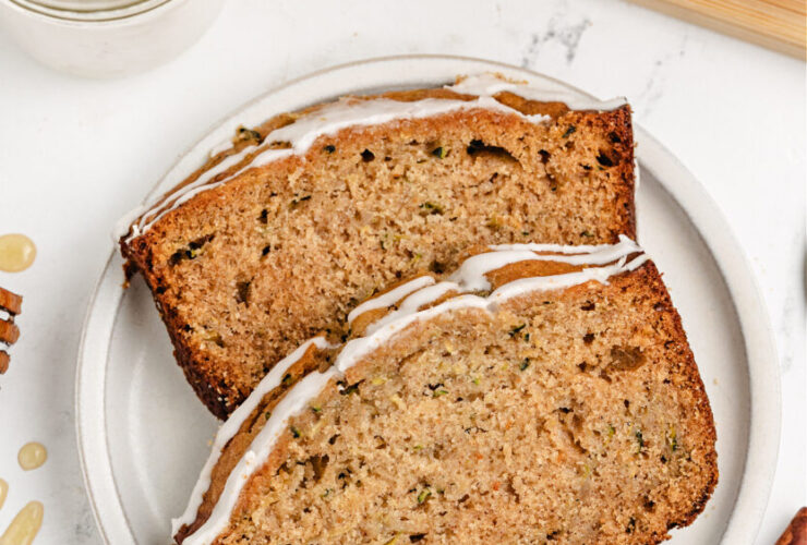 golden brown zucchini bread loaf sliced on wooden cutting board with butter and honey