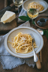 Spaghetti Carbonara served in a white ceramic bowl with freshly cracked black pepper and grated pecorino romano on top