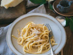 Spaghetti Carbonara served in a white ceramic bowl with freshly cracked black pepper and grated pecorino romano on top