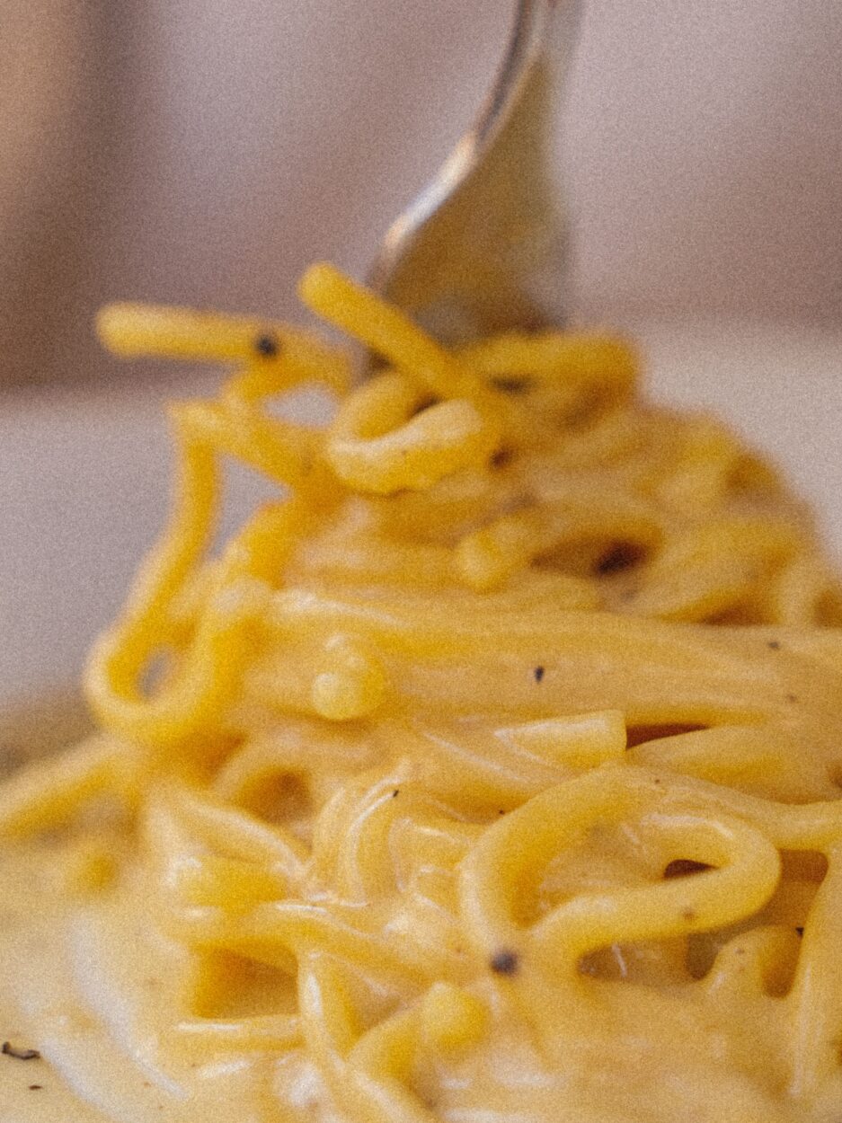 Close-up of Spaghetti Carbonara being twirled on a fork, showing the glossy sauce coating the pasta strands