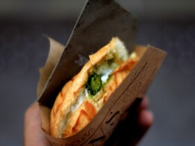 Stunning Banh Mi sandwich cut in half showing layers of marinated pork, pickled vegetables, fresh herbs, and pâté on crusty Vietnamese baguette