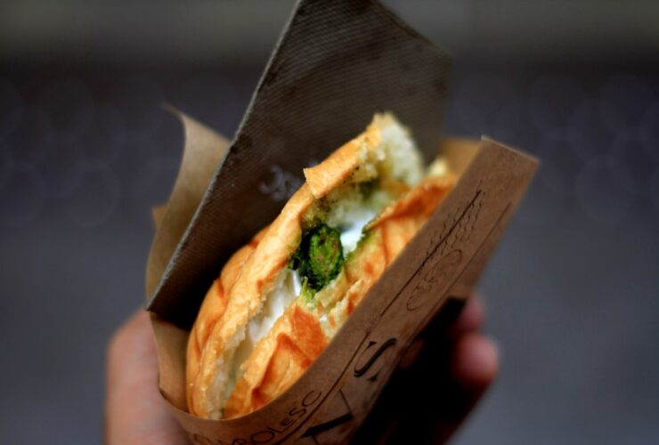 Stunning Banh Mi sandwich cut in half showing layers of marinated pork, pickled vegetables, fresh herbs, and pâté on crusty Vietnamese baguette