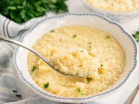 Buttered pastina served in white bowl with golden butter sauce and grated parmesan on top