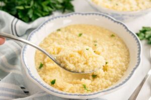 Buttered pastina served in white bowl with golden butter sauce and grated parmesan on top
