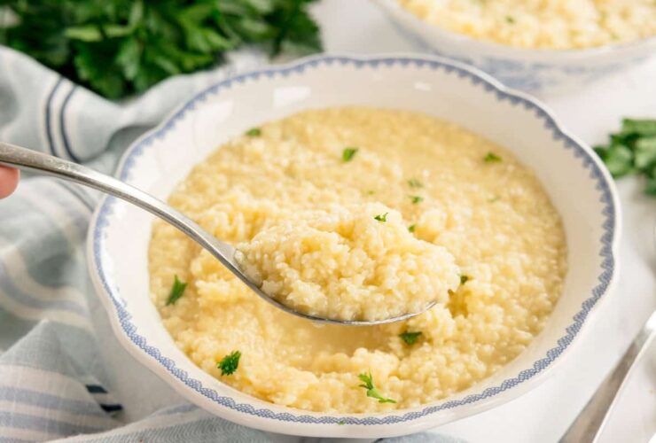 Buttered pastina served in white bowl with golden butter sauce and grated parmesan on top