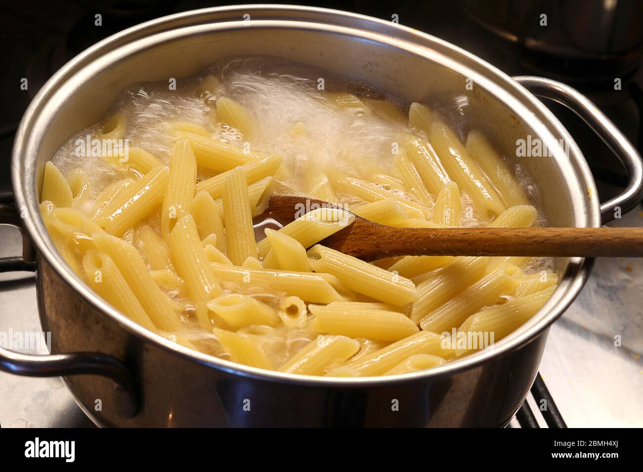 Pastina pasta cooking in boiling salted water with wooden spoon