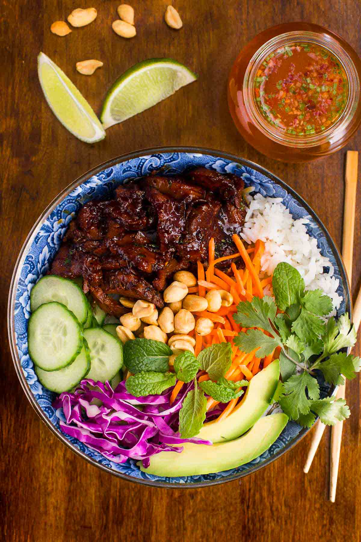 Raw pork shoulder pieces in red marinade in a glass bowl, showing the vibrant color and glossy coating