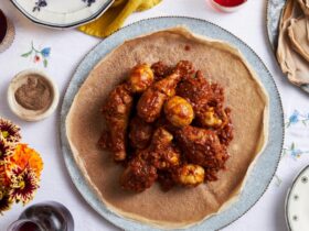 Ethiopian Doro Wat served in traditional clay bowl with injera bread, showing rich red sauce coating tender chicken with halved hard-boiled eggs