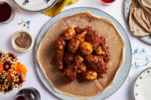 Ethiopian Doro Wat served in traditional clay bowl with injera bread, showing rich red sauce coating tender chicken with halved hard-boiled eggs