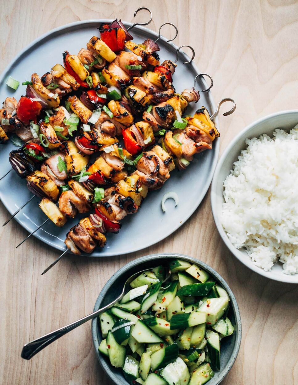 Grilled pineapple chicken skewer ingredients laid out flat — cubed chicken thighs, fresh pineapple chunks, sliced bell peppers, marinade in a bowl, garlic and ginger