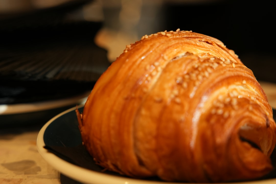 Close-up shot of a single cinnamon roll on a plate with cream cheese glaze dripping down the sides, showing the spiral pattern and tender texture