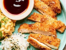 Golden crispy Japanese chicken katsu cutlets arranged on a white plate with shredded cabbage, katsu sauce, and lemon wedges, photographed from above with dramatic lighting