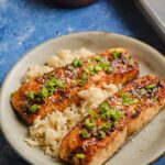 Perfectly glazed salmon fillet with caramelized miso coating, garnished with sesame seeds and scallions on a white plate