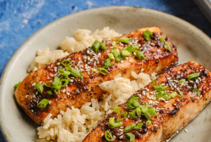 Perfectly glazed salmon fillet with caramelized miso coating, garnished with sesame seeds and scallions on a white plate