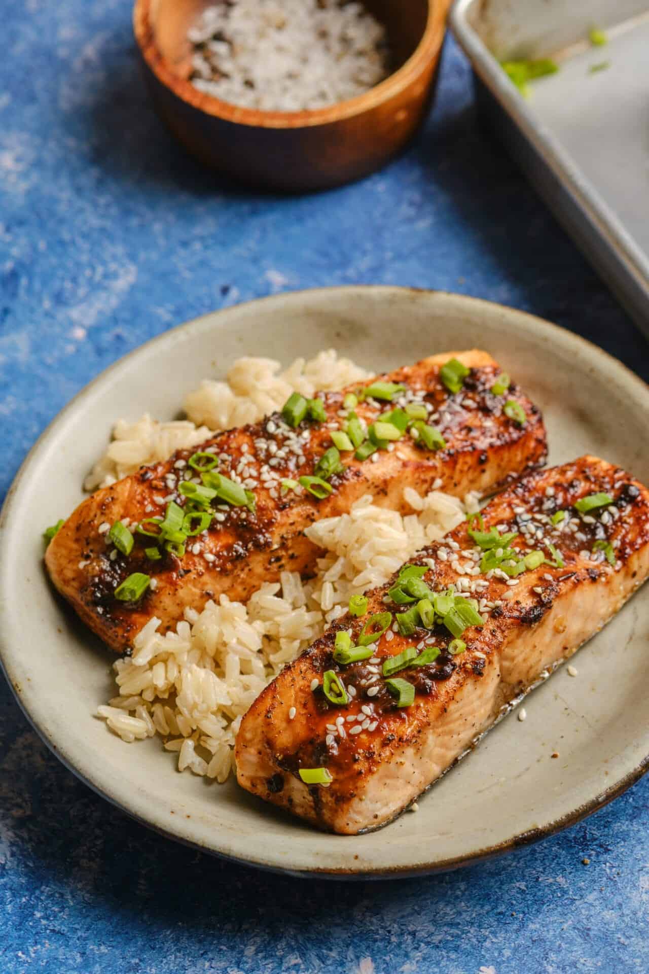 Perfectly glazed salmon fillet with caramelized miso coating, garnished with sesame seeds and scallions on a white plate