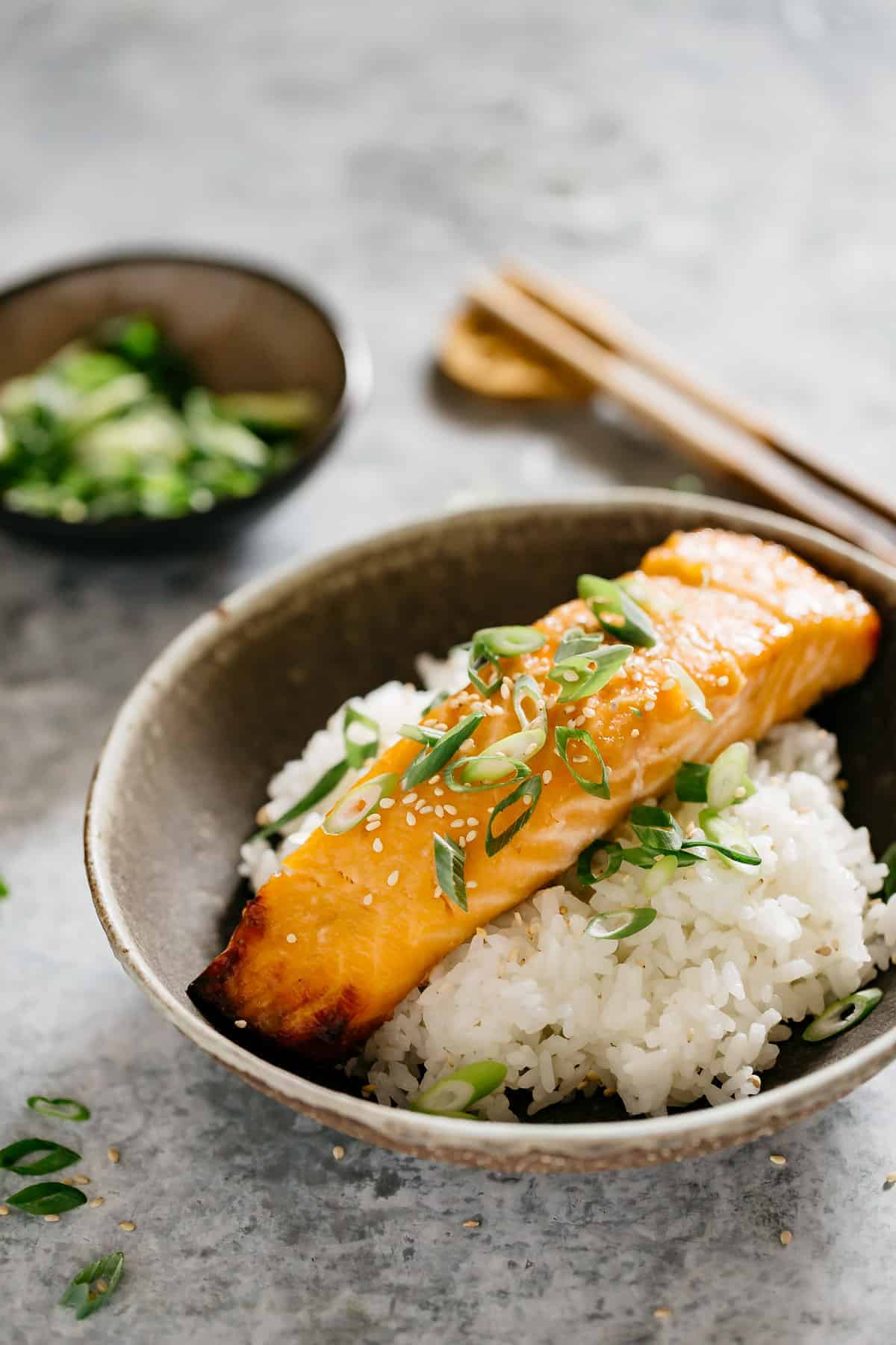 Raw salmon fillets being brushed with glossy miso glaze, showing the marinade process