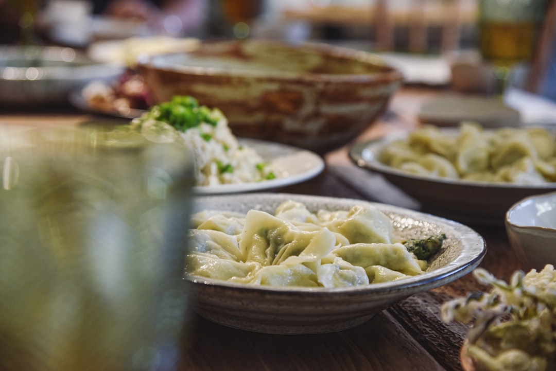 Close-up of a pierogi being cut open with a fork, showing the creamy potato-cheese filling steaming inside, garnished with fresh chives