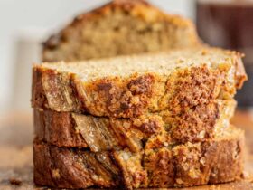 Sliced banana bread on a rustic wooden cutting board with golden brown crust and incredibly moist crumb visible
