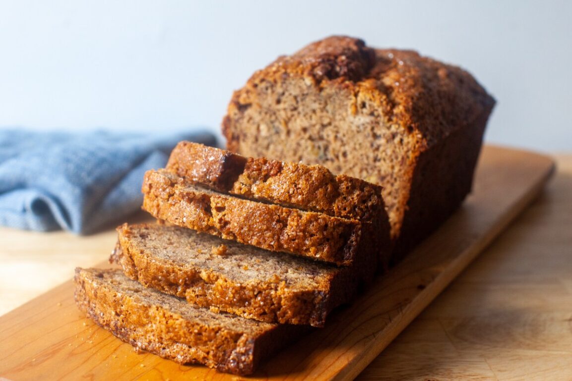 Close-up slice of banana bread showing incredibly moist, tender crumb with a pat of butter melting on top