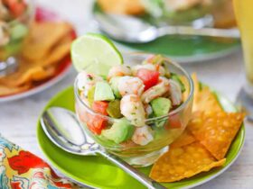 Gorgeous bowl of shrimp ceviche with vibrant pink shrimp, diced vegetables, and fresh herbs, garnished with lime wedges and served with crispy tortilla chips