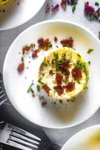 Perfectly golden Starbucks-style egg bites arranged on a white plate with fresh herbs garnish, showing their fluffy, cloud-like texture