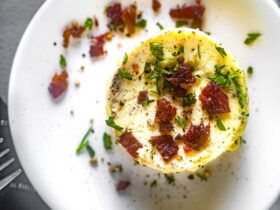 Perfectly golden Starbucks-style egg bites arranged on a white plate with fresh herbs garnish, showing their fluffy, cloud-like texture