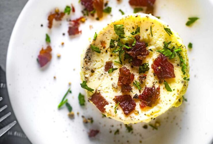 Perfectly golden Starbucks-style egg bites arranged on a white plate with fresh herbs garnish, showing their fluffy, cloud-like texture