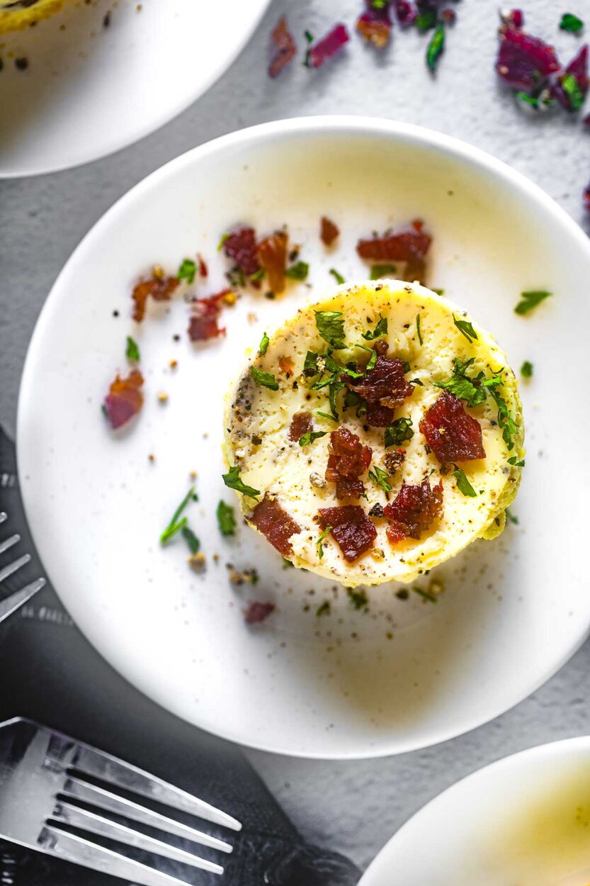 Perfectly golden Starbucks-style egg bites arranged on a white plate with fresh herbs garnish, showing their fluffy, cloud-like texture