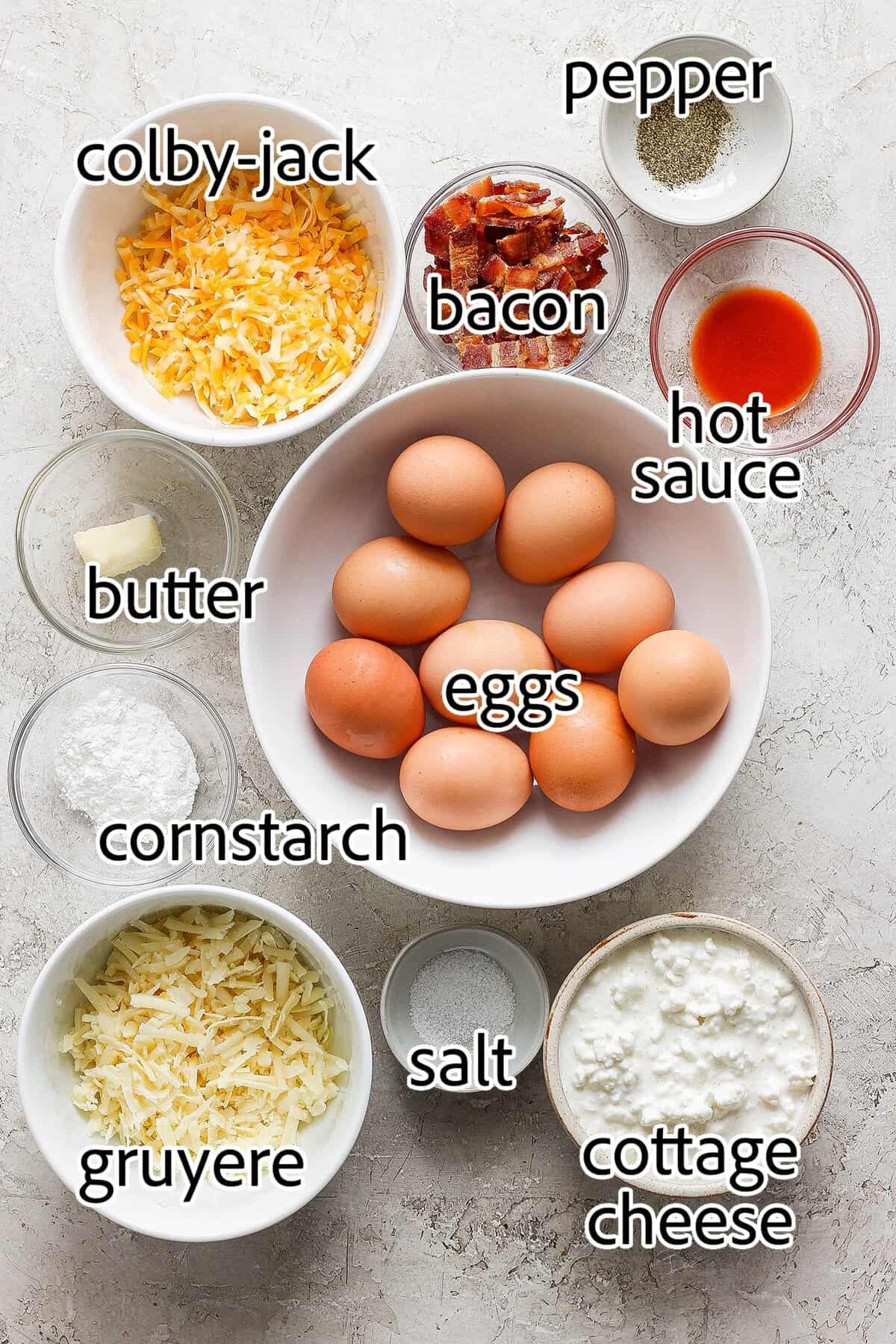 Ingredients laid out beautifully on a marble countertop showing eggs, cottage cheese, bacon, and cheese with measuring tools