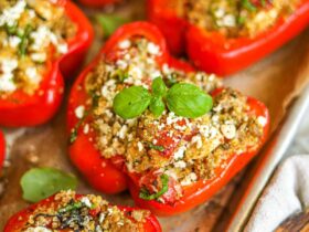 Overhead shot of colorful stuffed bell pepper boats filled with ground turkey and quinoa, garnished with fresh herbs and crumbled feta on a rustic wooden table