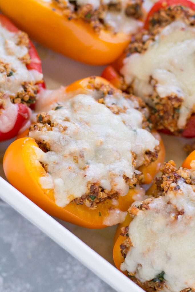 Close-up of a single stuffed bell pepper boat cut open to reveal the juicy ground turkey quinoa filling with crumbled feta and fresh herbs, steam rising, on a white plate