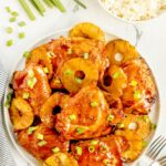 Huli Huli Chicken glazed with sticky pineapple BBQ sauce on a platter garnished with grilled pineapple slices and green onions