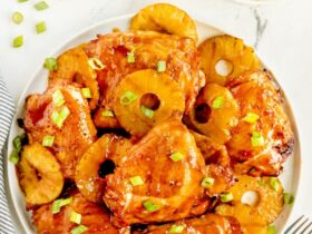 Huli Huli Chicken glazed with sticky pineapple BBQ sauce on a platter garnished with grilled pineapple slices and green onions