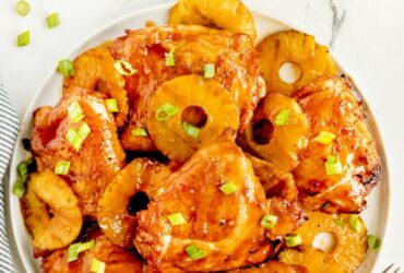 Huli Huli Chicken glazed with sticky pineapple BBQ sauce on a platter garnished with grilled pineapple slices and green onions